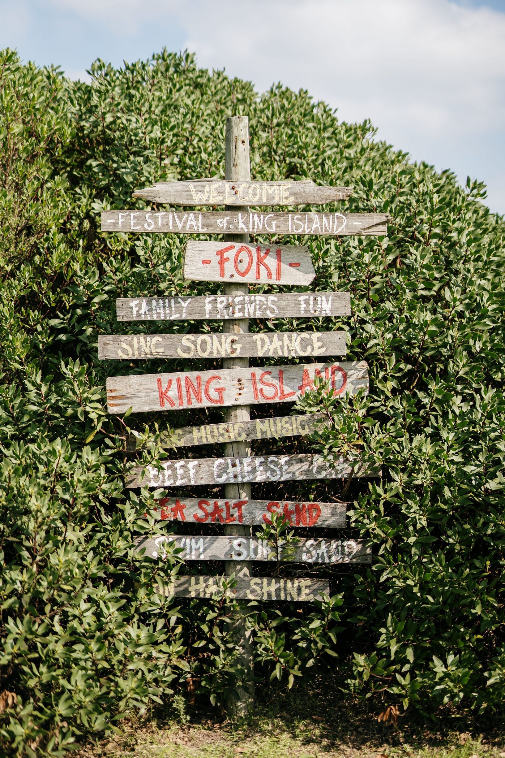 FOKI signpost hand-painted with festival slogans, set against coastal bush on King Island.